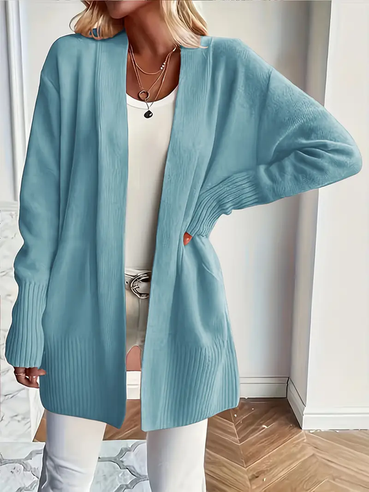 Person wearing a light blue cardigan over a white outfit in an indoor setting.